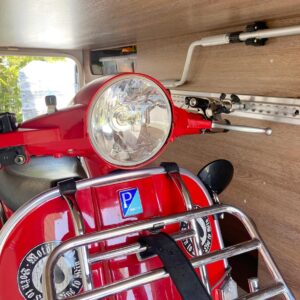 Vespa Motorroller steht in Rollerhalterung in Heckgarage